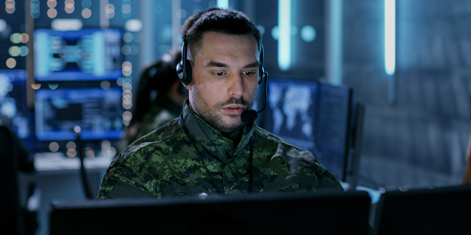 Person in camouflage and headset looks at computer screen